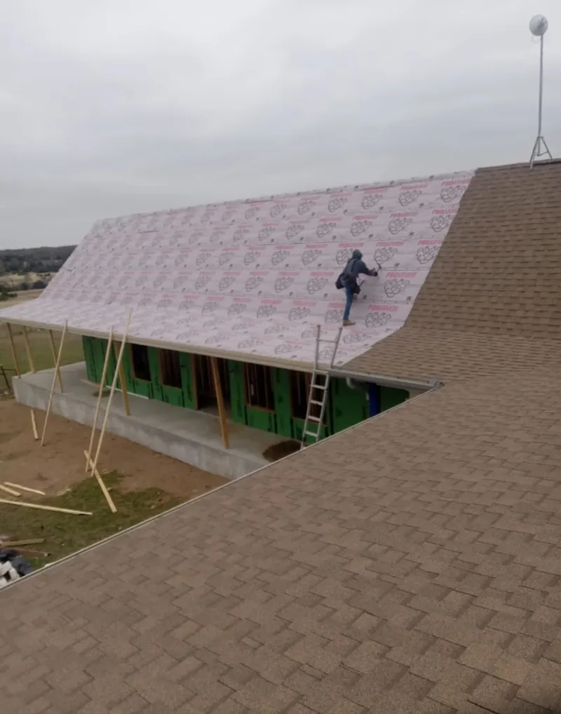 Worker preparing underlayment for a metal roof installation in Bonner Springs